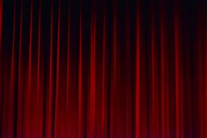 A red velvet curtain draped in folds against a dark background.