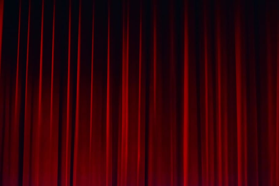 A red velvet curtain draped in folds against a dark background.